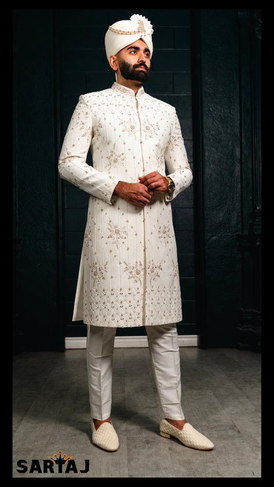 Ivory Dupion silk The Royal Edit groom sherwani featuring intricate floral embroidery in white, blush pink, and sage green threads, enhanced with subtle zari and tonal beadwork. Paired with a comfortable cotton lycra churidar for timeless elegance.