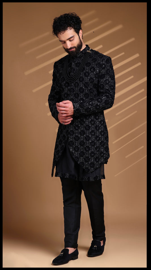 Black velvet Urban Nawab groom sherwani featuring all-over highlight embroidery and monochrome bead embellishments, paired with a sleek Dupion silk kurta and cotton lycra trousers.